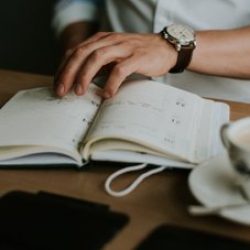 person-taking-notes-notebook-while-working-from-home